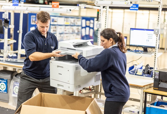Mann og kvinne på en fabrikk legger en skriver i en pappeske