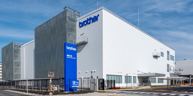Hvit og grå Brother-fabrikkbygning med blå himmel