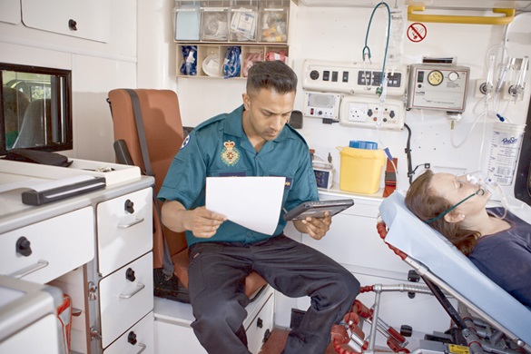 Ambulansepersonellsom sitter i en ambulanse med et nettbrett og en mobil skriver i Brother PJ700-serien