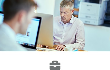 To menn jobber ved en datamaskiner på et kontor