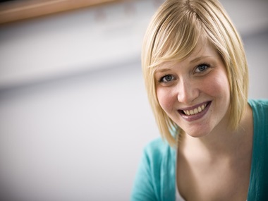 En kvinne i turkis genser som smiler
