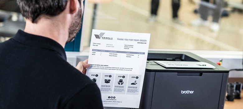 En lagerarbeider står ved en Brother laserskriver og holder i et dokument 