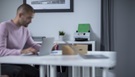 Mann som sitter å jobber på en pc med en skanner i bakgrunnen
