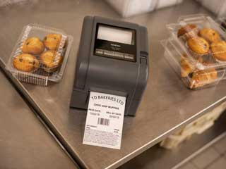 En Brother etkettskriver i TD4T-serien plassert på en stålbenk med bakevarer i et bakeri