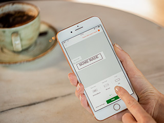 Kvinne som bruker Design & Print-appen for å designe en merkelapp mens hun er i en kaffebar og slapper av